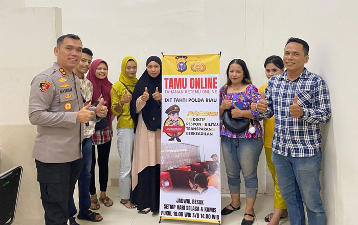 Dirtahti Polda Riau AKBP Hicca Alexfonso Siregar  (kiri) berfoto bersama petugas dan keluarga tahanan yang membesuk sambil mensosialisasikan Pilkada damai, Rabu (16/10/2024).