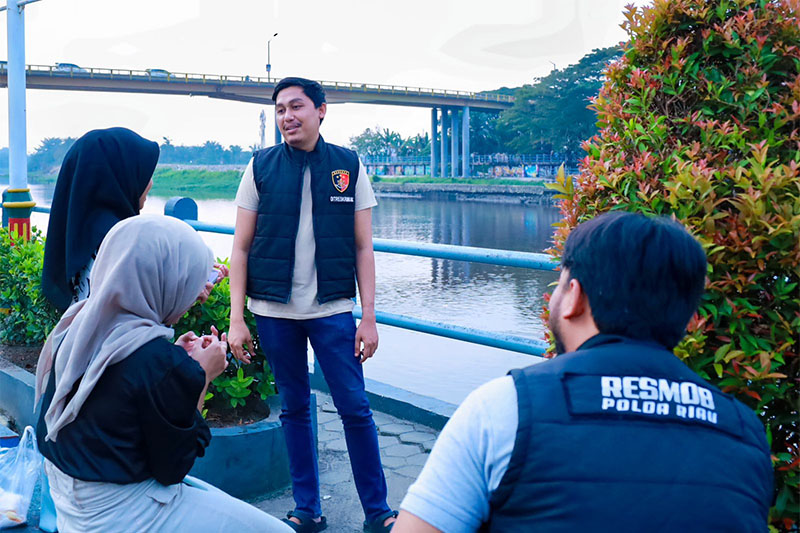 Personel Ditreskrimum Polda Riau Briptu M Rizki saat berbincang dengan muda-mudi yang santai sore di objek wisata Rumah Tuan Kadi, Pekanbaru, Kamis (31/10/2024).