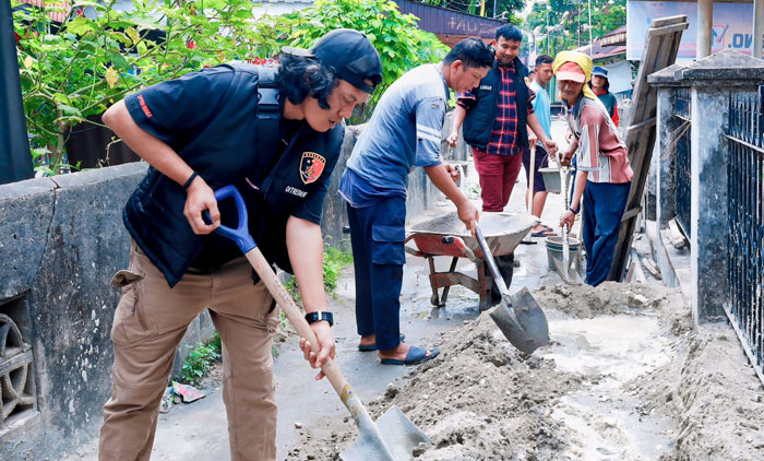 Personel Ditreskrimum Polda Riau Aipda Anton saat bergotong royong bersama warga, Jumat (1/11/2024).