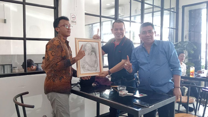 Muhammad Sehan Dwi Alfadhillah siswa kelas 3 SMA N 2 Tualang menyerahkan lukisan buatannya kepada calon Bupati Siak Ir H Irving Kahar Arifin di Dien Cafe Kecamatan Tualang, Kabupaten Siak