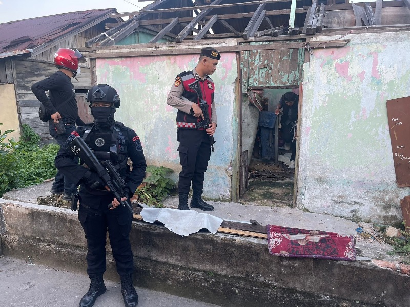 Petugas Satbrimobda dan Sat Sabhara Polda Riau saat berjaga ketika tim dari Ditresnarkoba melakukan penggeledahan di salah satu bangunan di Kampung Dalam, Pekanbaru, Jumat (8/11/2024).