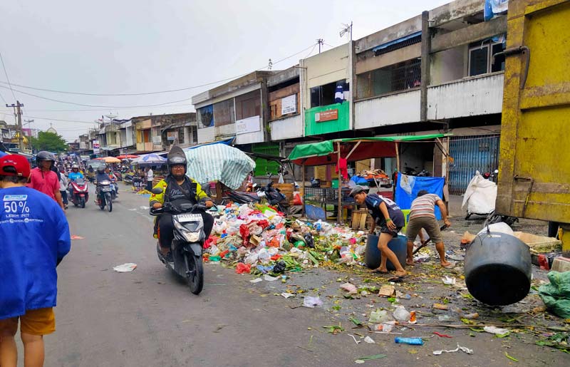 Pekerja mengangkut sampah yang berserakan di Jalan  Agus Salim, Pekanbaru,  baru-baru ini.