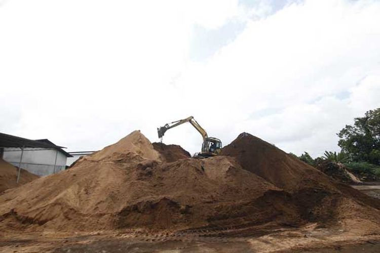 Operator mengoperasikan ekskavator untuk mengumpulkan sawdust di PT Marella Sukses Prima di Jalan Pasir Putih.