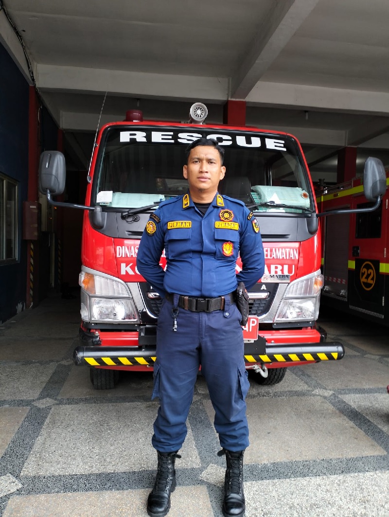 Personel rescue Dinas Pemadam Kebakaran dan Penyelamatan DPKP Kota Pekanbaru, Firman Setiawan bersikap siaga di depan mobil rescue, Senin (11/11/2024).