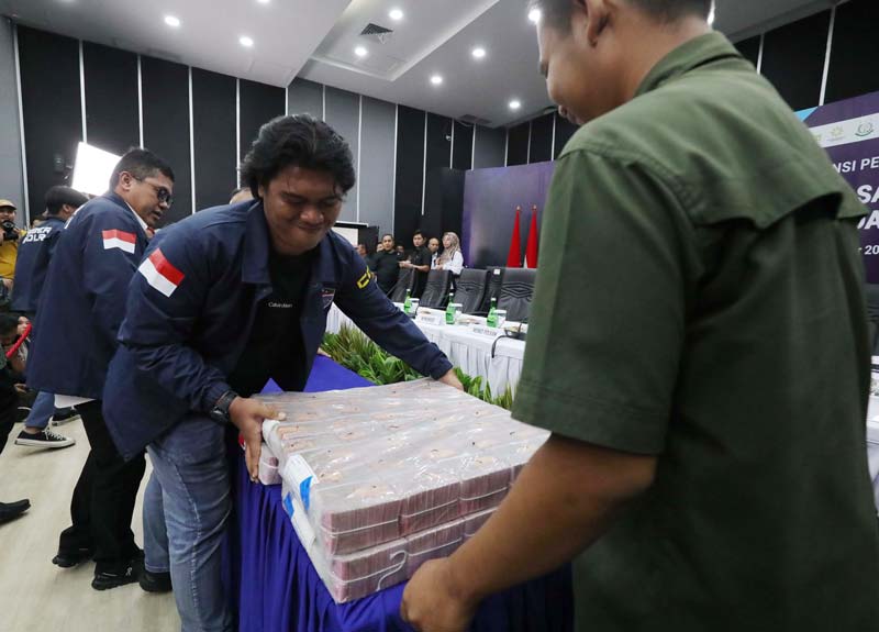 Petugas merapikan barang bukti uang hasil transaski judi online yang diamankan jelang konferensi pers