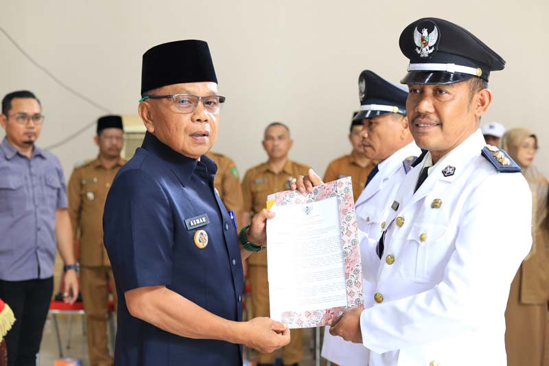 Plt Bupati Kabupaten Kepulauan Meranti H Asmar (kiri) menyerahkan SK kepada M Taufik (kanan) sebagai Pj Kades Wonosari dan Tauhid Yusro sebagai Pj Kades Alahair usai pelantikan, Senin (25/11/2024).