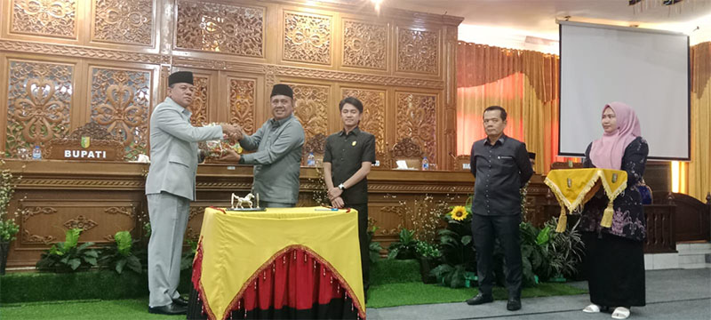 Ketua DPRD Kuansing H Juprizal SE MSi menyerahkan buku APBD 2025 pada Bupati Kuansing H Suhardiman Amby dalam paripurna, Sabtu (30/11) digedung DPRD Kuansing.