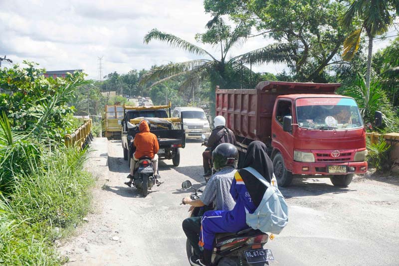 Pengendara melintas di jembatan Jalan Garuda Sakti KM 3, Kamis (28/11/2024). Kondisi jalan yang rusak di kawasan jembatan ini kerap menimbulkan kemacetan.