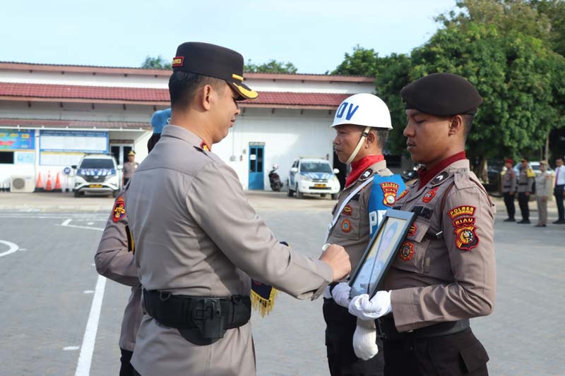 Kapolres Inhu AKBP Fahrian Saleh Siregar SIK MSi pada prosesi PTDH dengan cara memberi tanda silang di foto oknum anggota Polres yang dipegang oleh salah seorang personel, Ahad (1/12/2024).