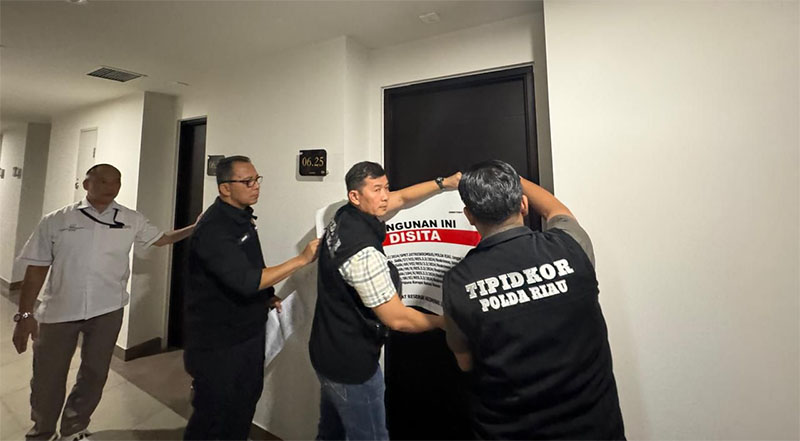 Penyidik Tipikor Ditreskrimsus Polda Riau saat memasang segel penyitaan unit apartemen di Batam, Kepulauan Riau, baru-baru ini.