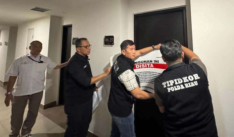 Penyidik Tipikor Ditreskrimsus Polda Riau saat memasang segel penyitaan empat unit apartemen di Batam, Kepulauan Riau, baru-baru ini.