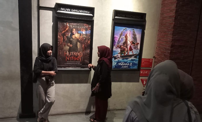 Penonton di Kota Pekanbaru berfoto didepan poster film "Hutang Nyawa" di CGV Transmart Pekanbaru, Jumat (6/12/2024) malam.