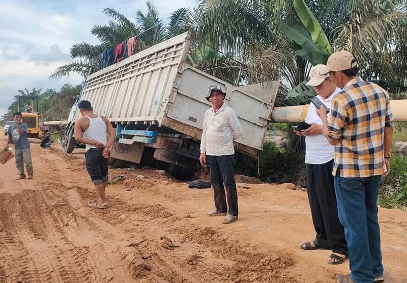 Kondisi ruas jalan di lintas Kecamatan Kubu rusak parah, beberapa waktu lalu. Satu unit truk yang sedang melintas terperosok masuk parit.