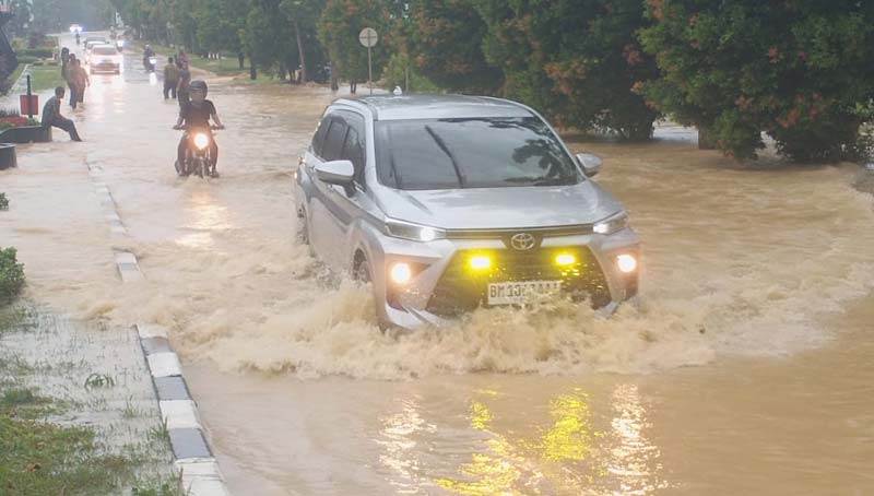 Para pengendara menerobos Jalan Sultan Syarif Hasyim Pangkalan Kerinci yang direndam banjir usai diguyur hujan dampak tidak adanya pembangunan drainase, baru-baru ini.