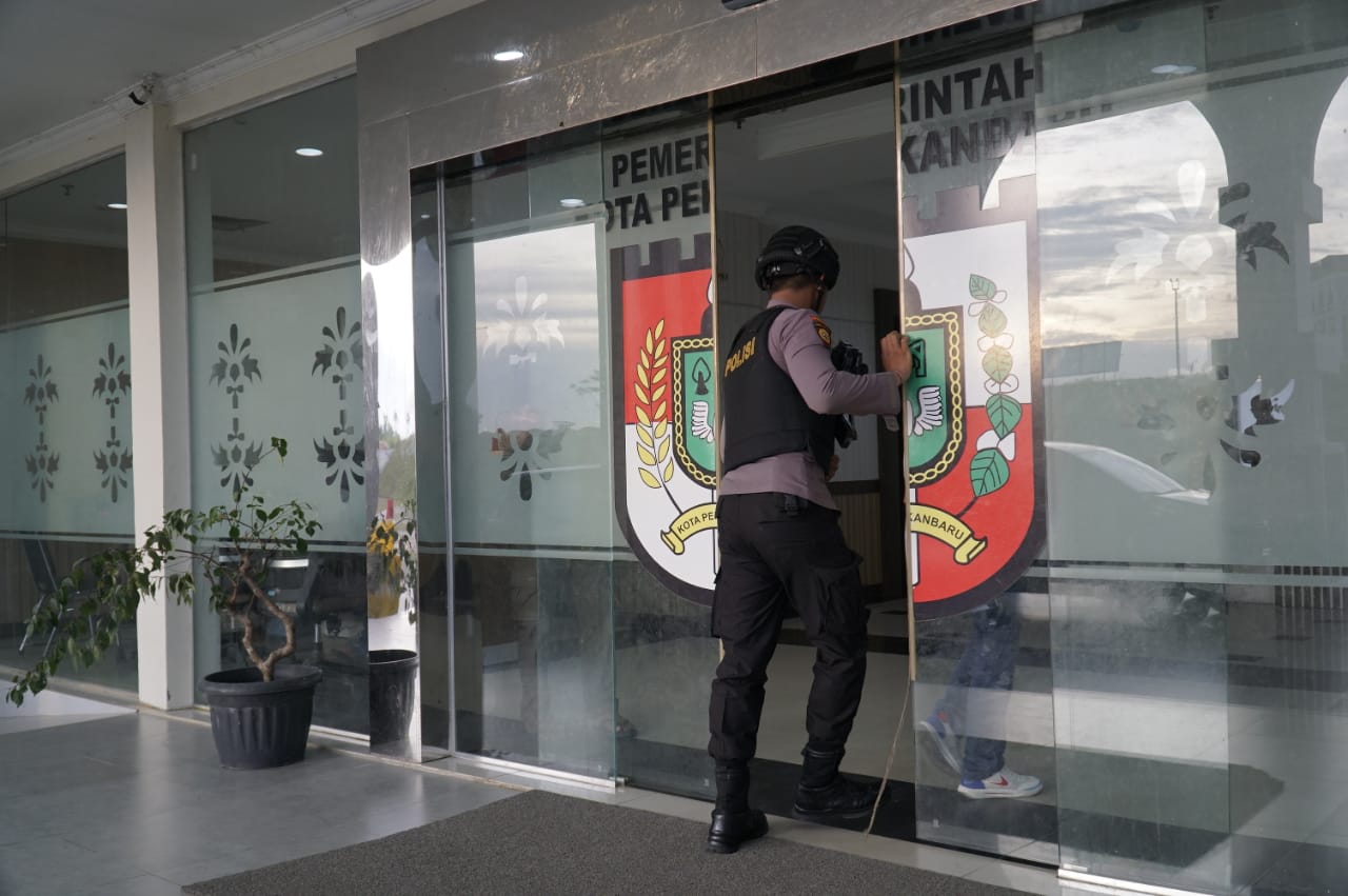 Polisi berjaga didepan pintu masuk Kantor Kesbangpol Kota Pekanbaru yang digeledah KPK bersama Kantor Dishub, di Komplek Perkantoran Walikota Pekanbaru di Tenayan Raya, Selasa (10/12/2024).