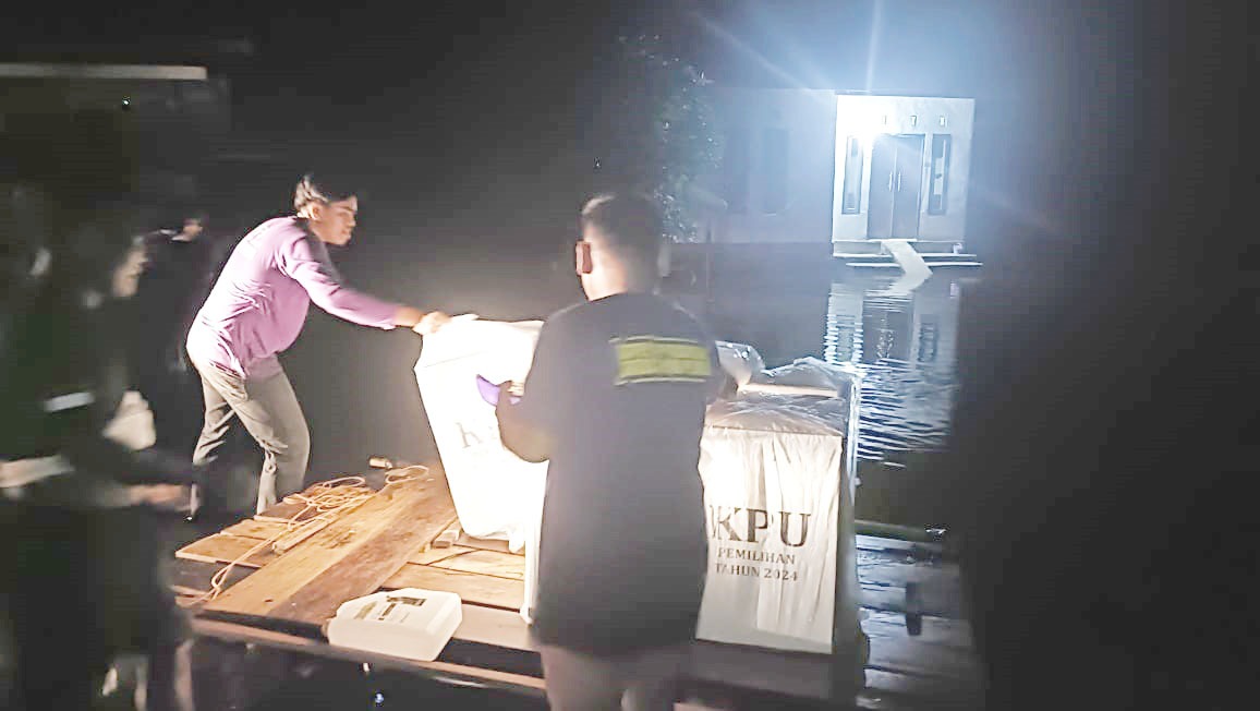 Petugas PPS TPS 02 Desa Sungai Besar Hilir Kecamatan Pucuk Rantau Kab. Kuansing, mencoba melansir logistik Pilkada dengan rakit papan di tengah banjir luapan Sungai Lingkue Desa Ibul, Rabu (27/11)
