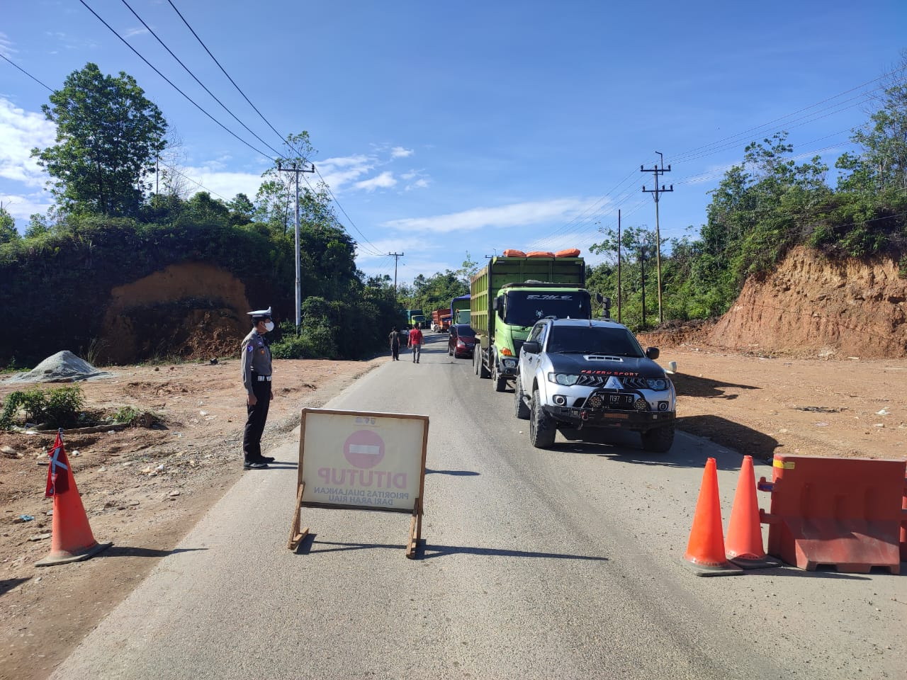 Personel Satlantas Polres Kampar mengatur arus lalu lintas di Jalan Lintas Riau-Sumbar Km 106-107 Desa Tanjung Alai, Kecamatan XIII Koto Kampar, Kabupaten Kampar, Sabtu (14/12/2024).
