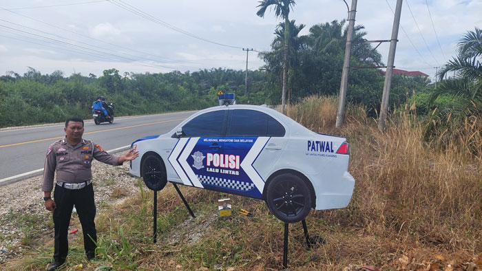 Personel Sat Lantas Polres Kuansing memasang kamuflase mobil lantas di ruas jalan Teluk Kuantan-Pekanbaru .