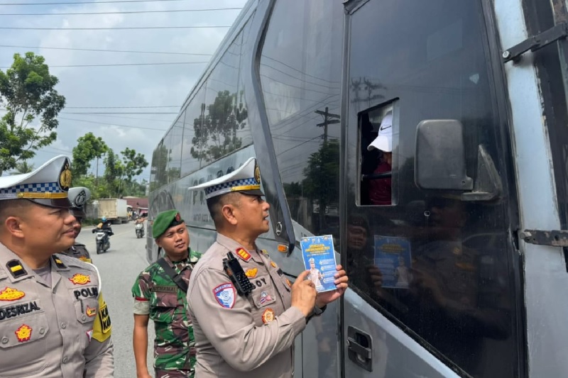 Kasatlantas Polres Kuansing AKP Boy Setiawan SAP MSi bersama personel membagi-bagikan brosur keselamatan berkendara dalam sosialisasi Operasi Lilin  Lancang Kuning 2024, Jumat (27/12/2024).