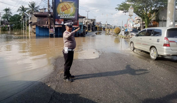 Personel Satlantas Polres Rohul terlihat tetap memantau surutnya banjir di ruas Jalan Tuanku Tambusai sekaligus mengatus arus lalulintas di Kota Pasirpengaraian menuju batas Sumut, Ahad (29/12/2024)