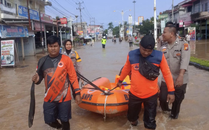 Personil BPBD, Polres Rohul membawa perahu karet saat menerobos genangan banjir yang merendam ruas jalan Tuanku Tambusai. Arus Lalulintas dialihkan ke Jalan Lingkar Km 4 Pasirpengaraian. Ahad (29/12)