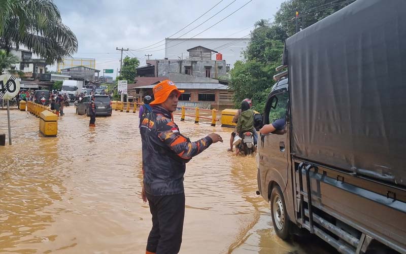 Petugas Badan Penanggulangan Bencana Daerah Indragiri Hilir membantu mengatur lalu lintas yang terganggu akibat banjir