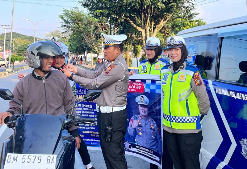 Kasat Lantas Polres Inhu, AKP Eri Asman SH didampingi anggota membagikan helm gratis kepada warga yang melintas, belum lama ini.