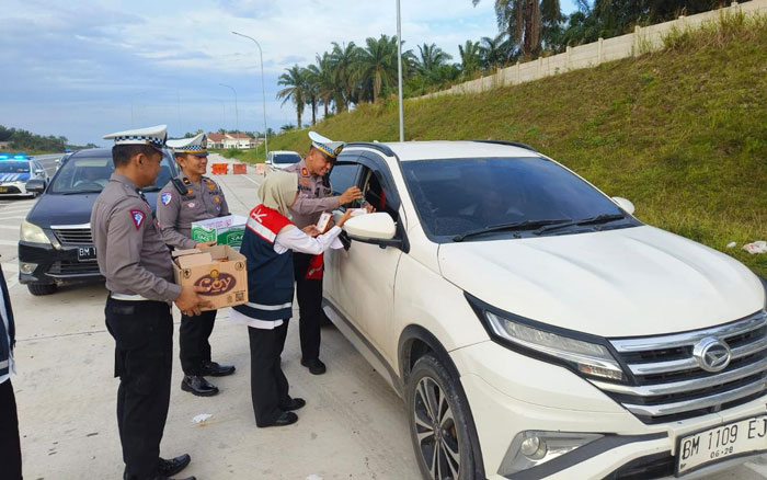 Kasat Lantas AKP Kaliman Siregar bersama KBO Satlantas Ipda Dodi dan Kanit Kamsel Ipda Ariawan membagikan air mineral dan roti di Km 46 B tol Pekanbaru-Dumai (Permai) pada Senin (30/12/2024).
