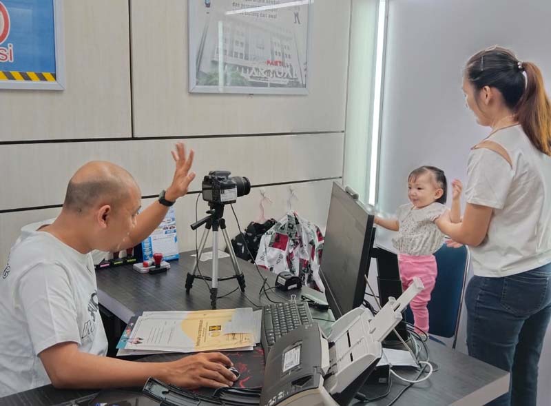 Salah seorang pemohon dan balitanya mela&shy;kukan perekaman paspor di Kantor Imigrasi Kelas II TPI Selat Panjang