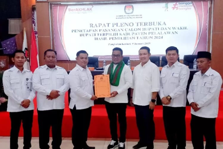 Ketua KPU Pelalawan, Bapri Naldi menyerahkan salinan berita acara dan keputusan KPU kepada H Zukri dalam Rapat Pleno Terbuka penetapan Bupati dan Wakil Bupati Pelalawan terpilih.