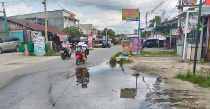 Pengemudi sepeda motor melintas di Jalan Pemda, Pangkalankerinci yang tergenang air akibat tidak adanya pembangunan drainase, beberapa waktu lalu.