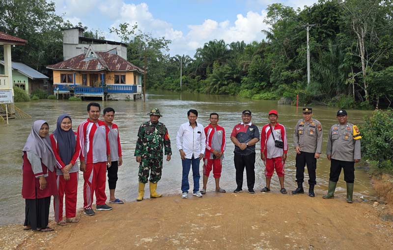 Kapolsek Ukui AKP Rudi Hardiyono SH bersama pihak kecamatan foto bersama usai meninjau kondisi banjir yang merendam akses badan jalan di Desa Lubuk Kembang Bunga, Pelalawan, Jumat (10/1/2025) siang.