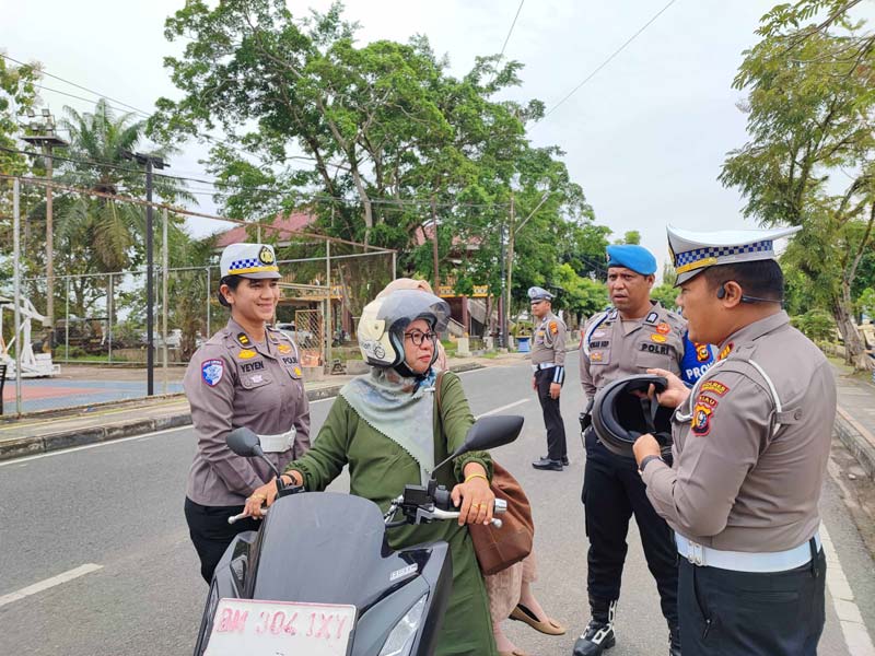 Kasat Lantas Polres Inhu, AKP Eri Asman SH didampingi anggota  membagikan helm gratis kepada warga yang terjaring saat melintas di depan Mapolres Inhu, Senin (13/1/2025).
