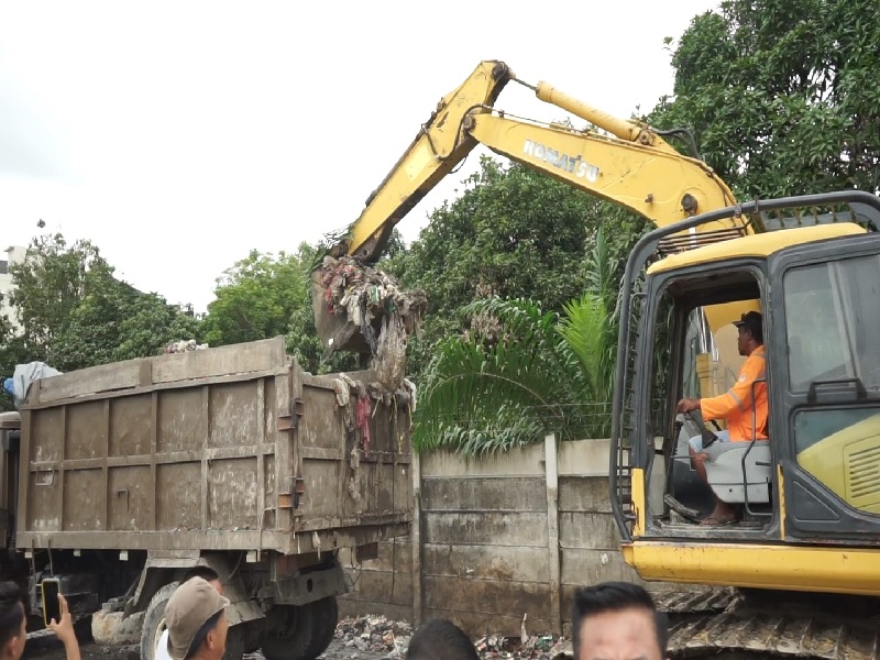 Pekerja menggunakan alat berat melakukan pengangkutan sampah yang berserakan di Jalan Laos Kecamatan Payung Sekaki Pekanbaru, Rabu (15/1/2025).