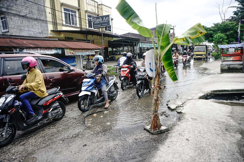 Pengendara menghindari badan Jalan Suka Karya, Kecamatan Tuah Madani, Pekanbaru yang kembali rusak dan ditanami pohon pisang oleh warga sekitar, Selasa (21/1/2025).