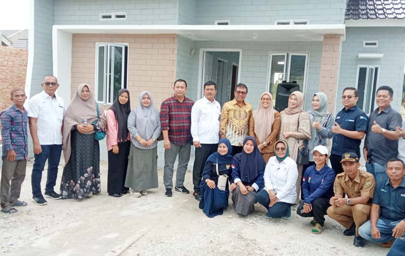Direktur Operasional PT Semen Padang Pri Gustari Akbar (enam kiri) dan Ketua DPD REI Riau Elvi Supryadi (tujuh kiri) foto bersama dengan penerima bantuan rumah