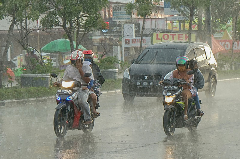 Pengendara sepeda motor&nbsp;menerobos&nbsp; hujan&nbsp;saat melintas di Jalan HR&nbsp; Soebrantas, Kota Pekanbaru, Senin  (27/1/2025).