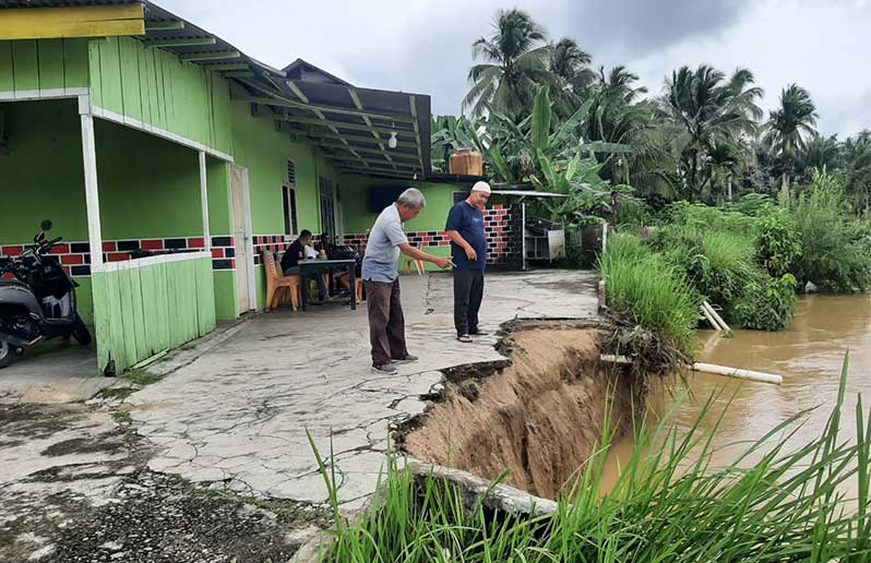 Zulfi, warga Pauh Angit Pangean, Kuansing, yang rumahnya terancam ablas melihat kondisi tebing di belakang rumahnya runtuh, Selasa (28/1/2025).