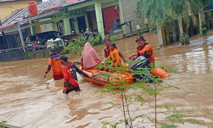 Anggota BPBD Rohul terlihat mengevakuasi warga yang rumahnya terendam banjir menggunakan perahu karet di Desa Babussalam.