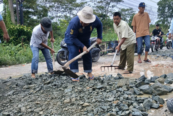 Warga yang  tinggal di sekitar Jalan Suka Karya Desa Tarai Bangun, Kecamatan Tambang, Kabupaten Kampar  bergotong royong menimbun memperbaiki jalan yang rusak, Rabu (29/1/2025).