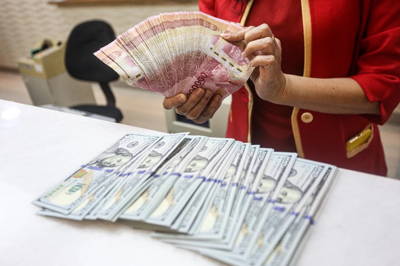 ILUSTRASI. Karyawati tunjukkan mata uang rupiah dan dolar AS di tempat penukaran uang asing di Jakarta, beberapa waktu lalu. Google error bikin nilai tukar rupiah jadi Rp8 ribu per dolar AS.