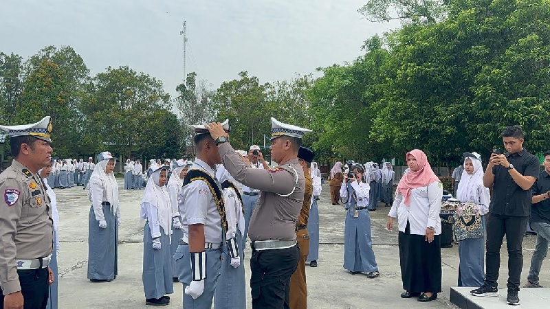 Kasatlantas Polres Siak AKP Kaliman SH MM memakaikan topi saat melantik PKS SMAN 1 Siak di lapangan sekolah, Senin (3/2/2025).