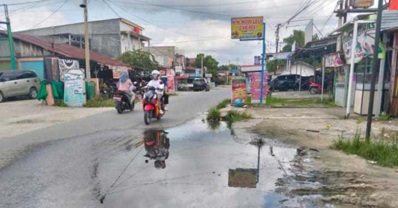 Pengemudi sepeda motor melintas di Jalan Pemda, Pangkalankerinci yang tergenang air akibat tidak adanya pembangunan drainase, Senin (3/2/2025).