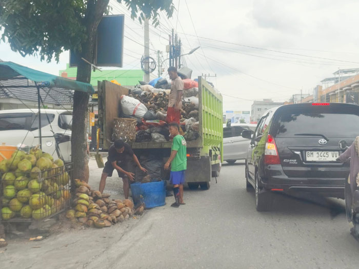 Petugas kebersihan nampak mengangkut sampah kelapa muda di Jalan Delima, Panam Pekanbaru, Rabu (5/2/2025).