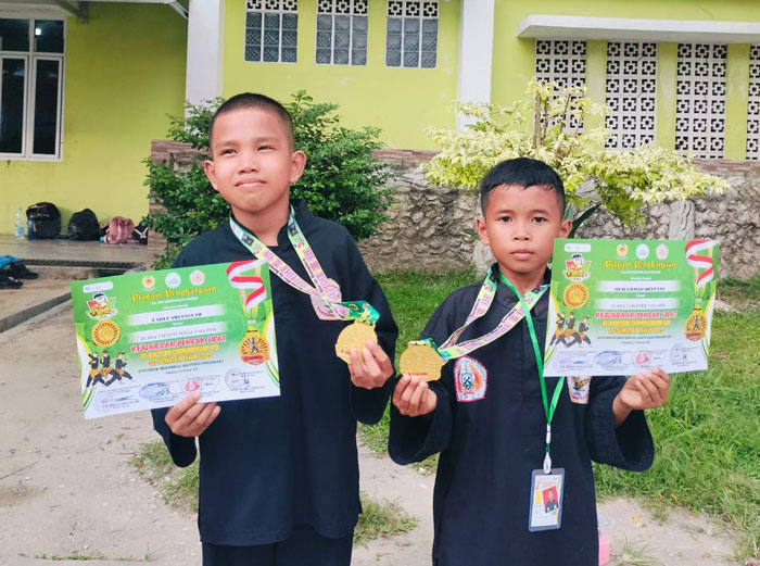Fadli Ariansyah (kiri) dan Muhammad Bintang menunjukkan medali emas yang diraih pada Kejuaraan Pencak Silat Al-Kautsar.
