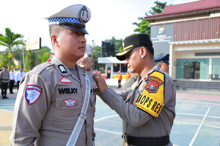 Wakapolres Inhil Kompol Riski Hidayat memasangkan pita tanda operasi lalu lintas kepada personel Polres Inhil, Senin (1/2/2025).