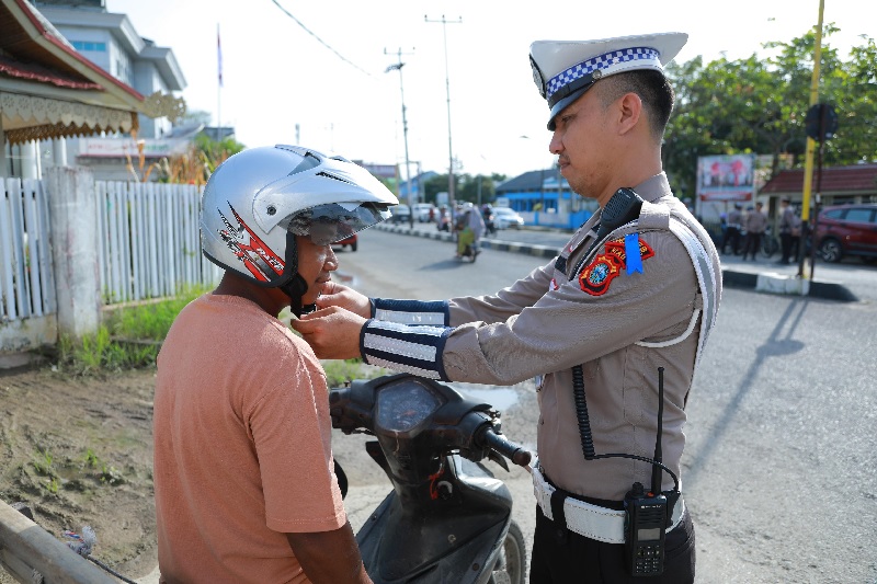 Personel Satlantas Polres Inhil saat membagikan dan memasangkan helm ke pengendara