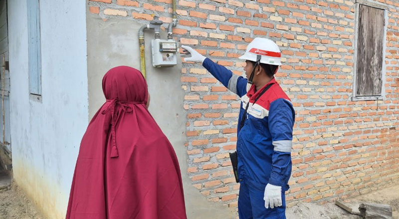 Petugas dari PGN berdialog dengan warga saat mengecek meteran gas di Desa Pinang Sebatang, Tualang, Siak, baru-baru ini.