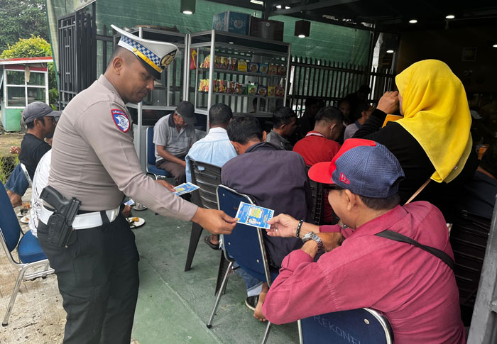 Kanit Regident Polres Inhil Ipda Jimy Lano bagikan selembaran tentang keselamatan lalu lintas.