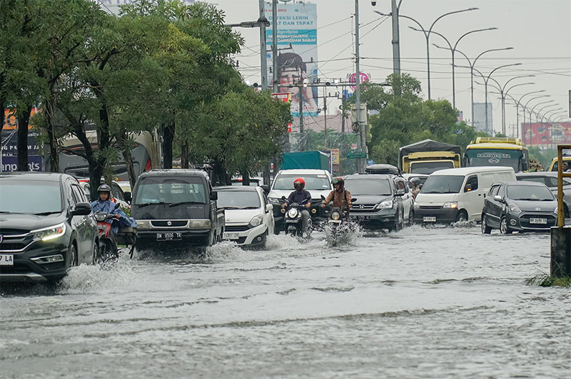 Antrean Kendaraan bermotor menerobos genangan banjir saat melintas di Jalan HR Subrantas Pekanbaru, Senin (24/2/2025).